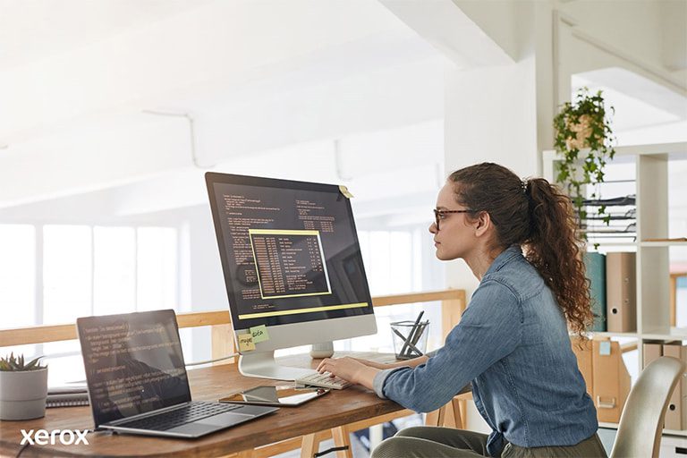 Een vrouw aan haar bureau, bezig met een computer en laptop, demonstreert productiviteit in een moderne werkruimte. Een vrouw aan haar bureau, bezig met een computer en laptop, demonstreert productiviteit in een moderne werkruimte.