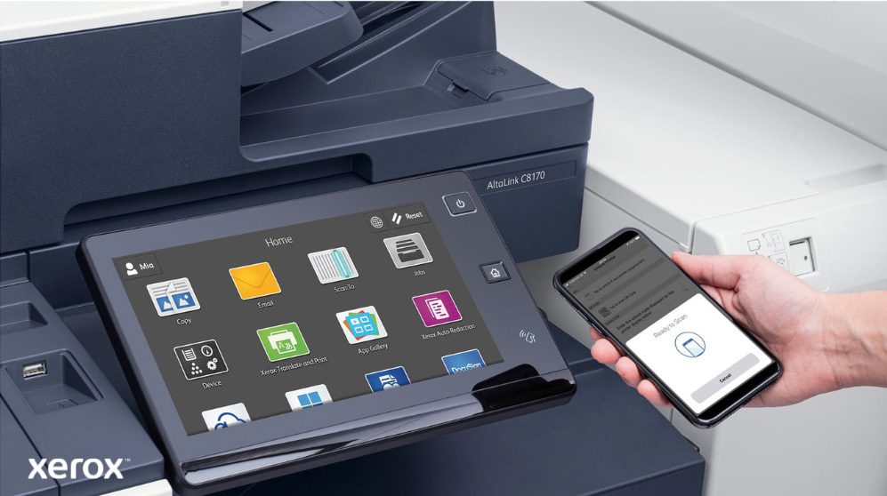 Een close-up van de hand van een persoon die een smartphone vasthoudt, die draadloos is verbonden met het touchscreen-bedieningspaneel van een multifunctionele Xerox-printer. Hierop zijn de naadloze mobiele print- en scanmogelijkheden van Xerox ConnectKey te zien.
